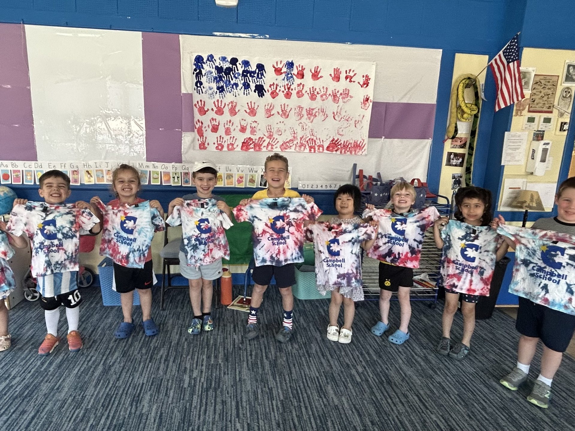 Children at The Campbell School holding up their painted art smocks