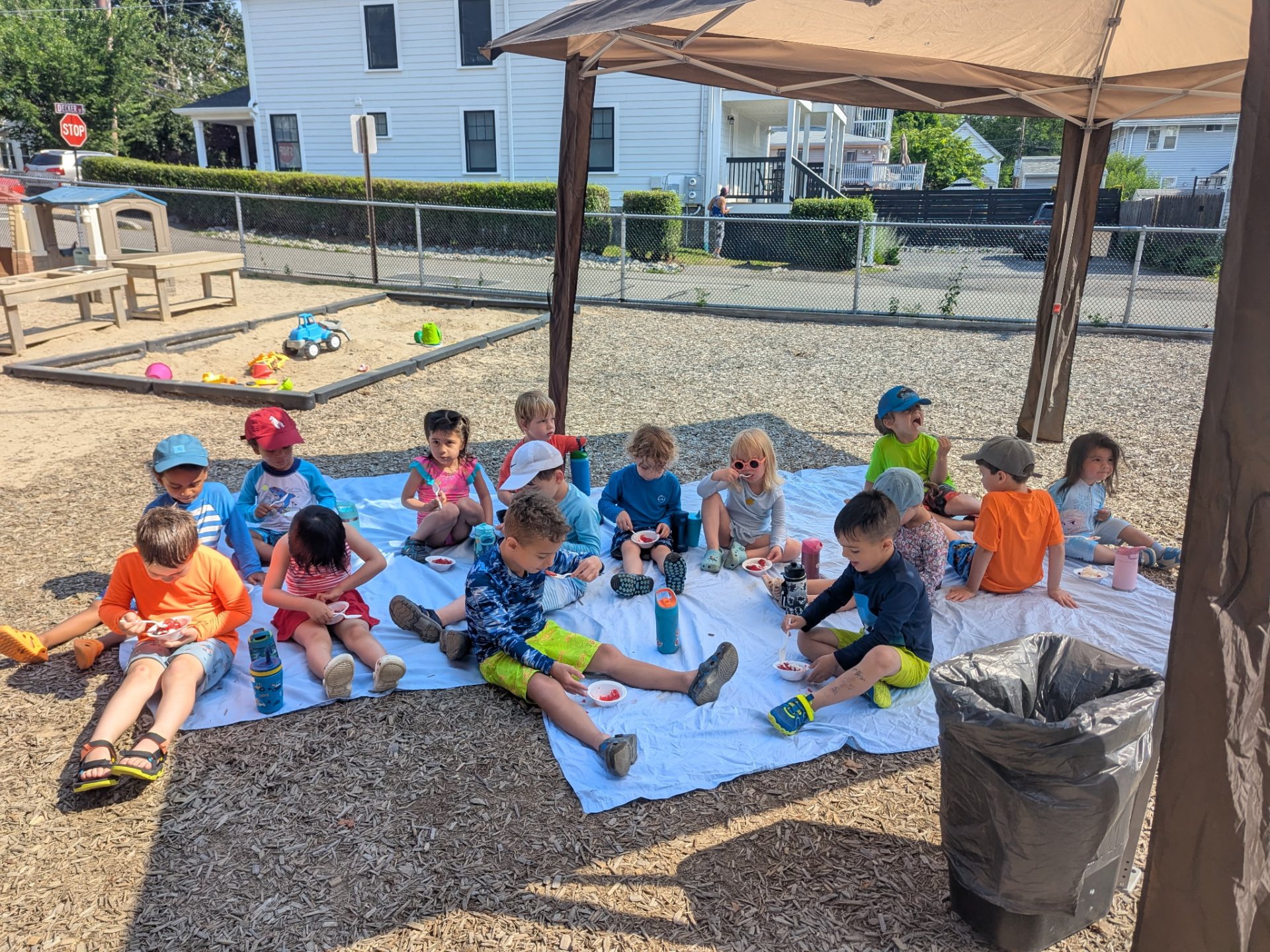 Children sitting together on a blanket in the outdoor play yard