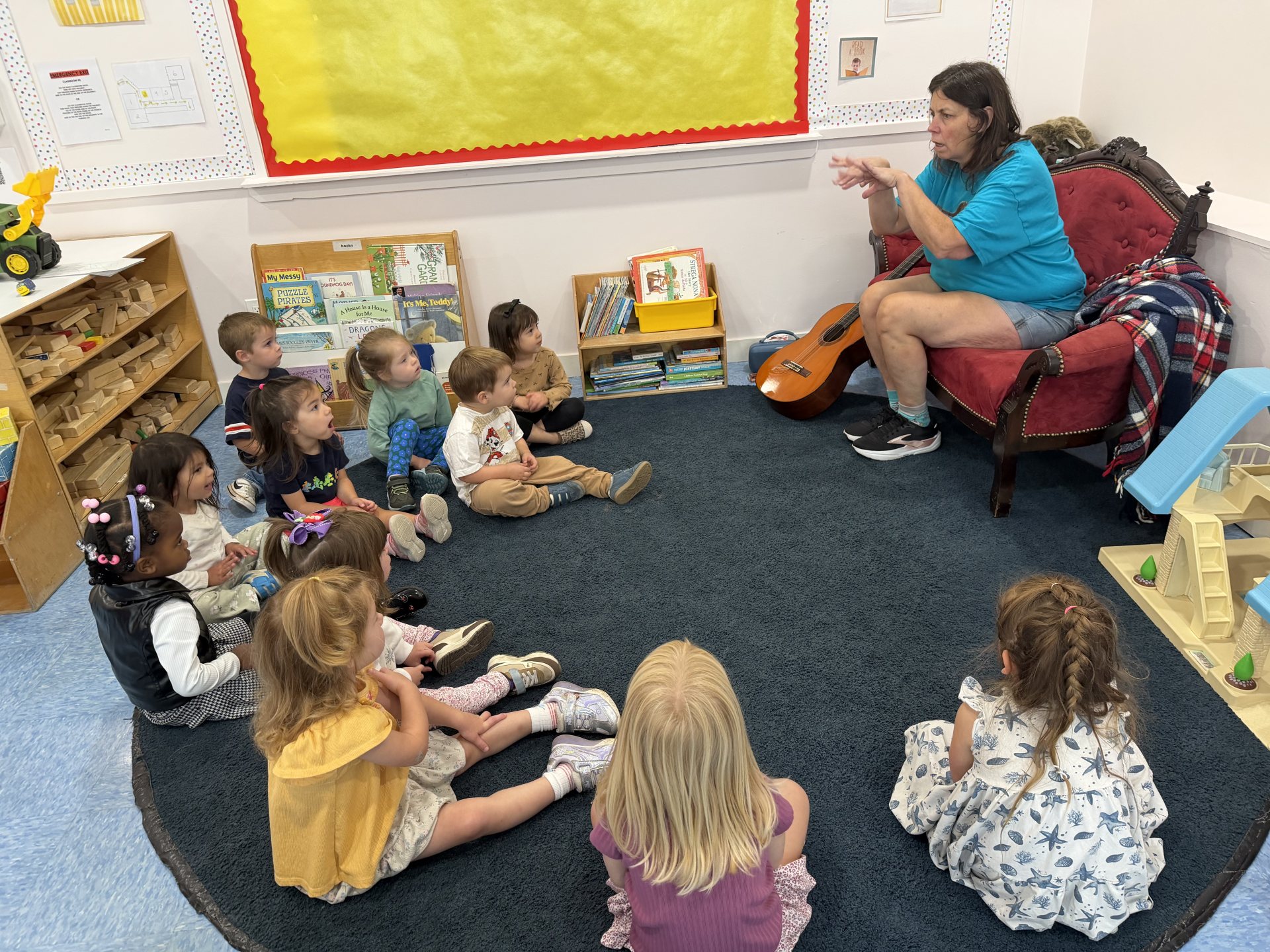 Children gathered on the rug listening to their teacher at story time